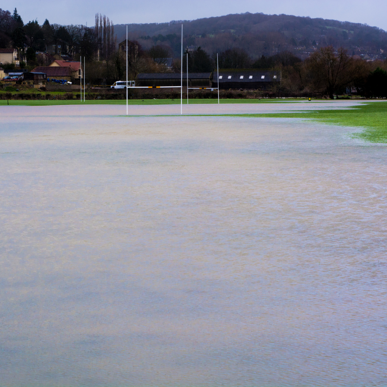 A flooded sports field with water covering the grass, illustrating how climate change can disrupt outdoor sports activities.