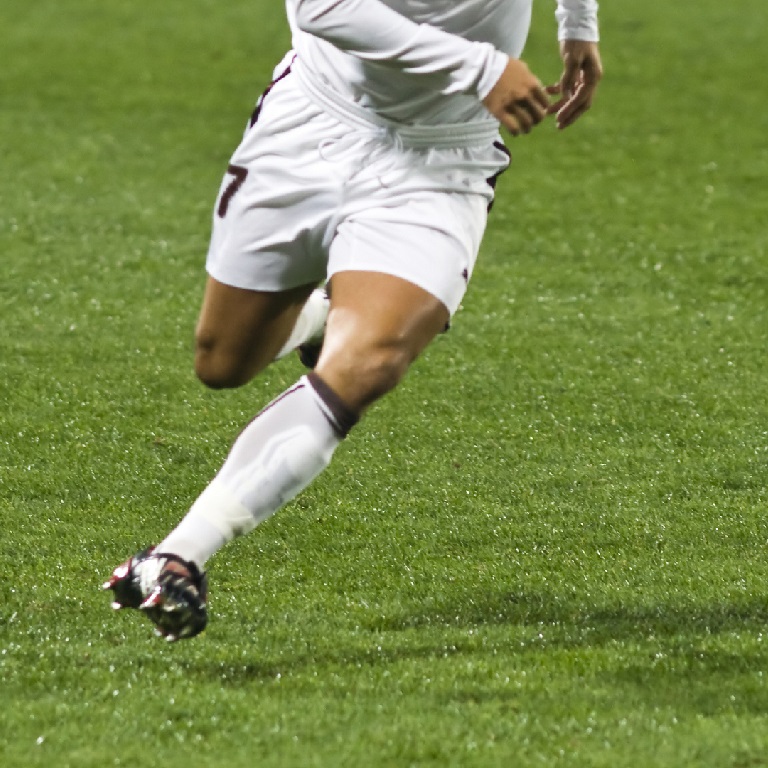 Bottom half of professional footballer running towards ball