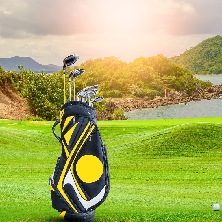 Sun beam shining down on a golf bag full of clubs on a fairway with islands in the background 