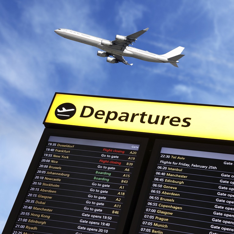 Airport flight information on a large screen international departure board and airplane flying overhead