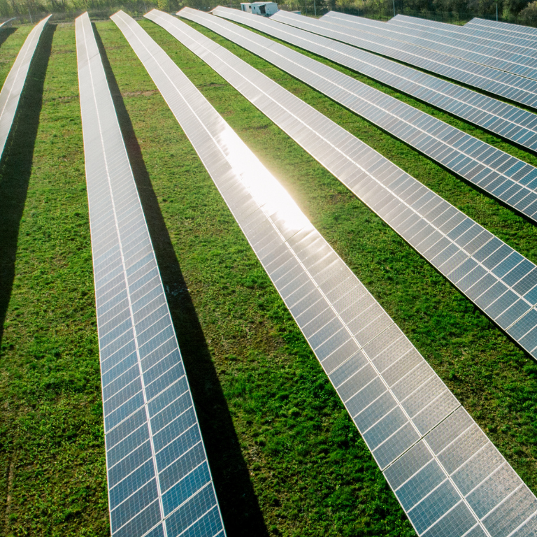 A large field with multiple rows of solar panels, highlighting renewable energy and sustainability efforts in sports infrastructure.
