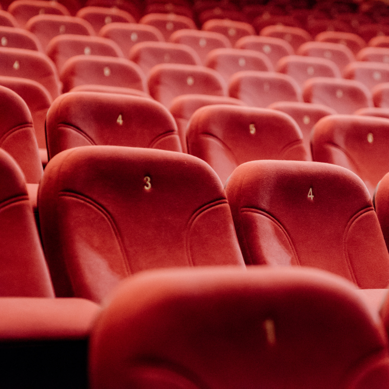 Rows of red theatre seats in an auditorium, symbolising the concept of elevating or improving your environmental strategy through a professional setting.
